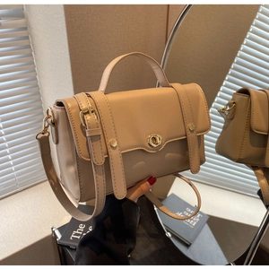 Gros plan détaillé du sac bandoulière beige avec fermoir rotatif doré et poignée