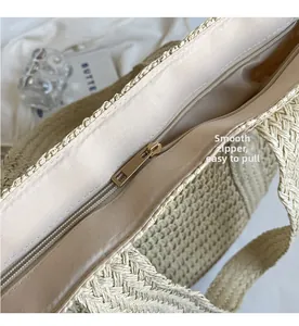 Detail of a straw tote bag showing the smooth gold zipper and beige satin lining interior