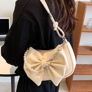 Cream bow shoulder bag with pearl chain and floral charms shown on model back view