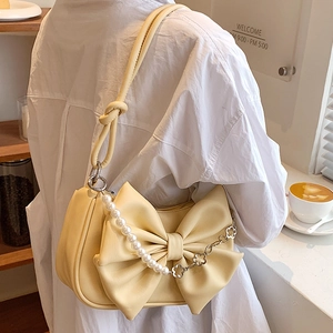 Chic cream leather shoulder bag with a large bow and pearl flower chain detail