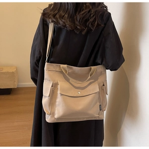 Detail view of khaki canvas tote bag with functional exterior pockets and side fashion tag