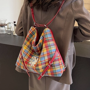 Vintage plaid backpack with red leather straps and metal chain on a female model