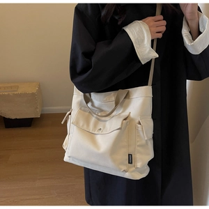 Detail view of large canvas tote bag with functional pockets and khaki crossbody strap