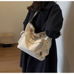 Side view of beige canvas tote bag with multi-pocket design and adjustable shoulder strap