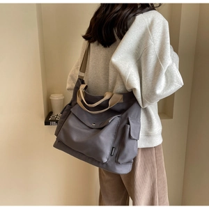 Detail shot of canvas tote bag with fashion tag and khaki strap on a model