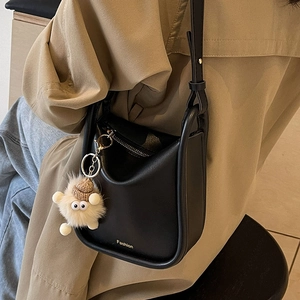 Retro black leather bucket bag with gold logo and plush sheep charm on shoulder strap