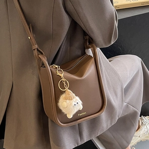 Brown matte leather bucket bag with plush monster charm and Fashion logo gold lettering