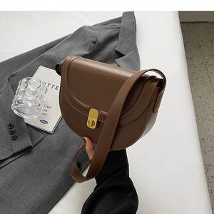 Classic dark brown leather saddle bag with gold metal buckle shown in a lifestyle setting