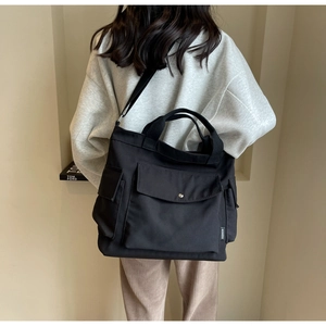 Detail of black canvas tote bag with multiple pockets and fashion label on the side