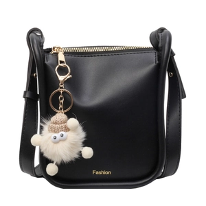 Retro black leather bucket bag with gold hardware and a cute white plush monster charm