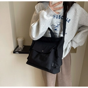 Detail of black canvas tote bag with multi-pocket design and adjustable shoulder strap