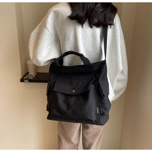 Detail showing the large capacity and multiple functional pockets on the black canvas tote bag