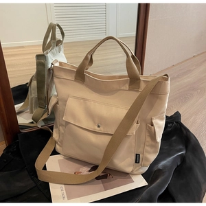 Detail view of beige canvas tote bag with multi-pockets and adjustable crossbody strap
