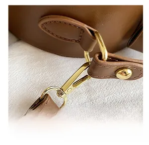 Close-up of golden metal hook clasp and stitching on brown textured leather bag