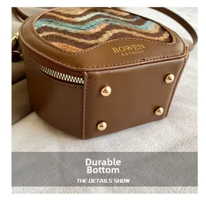 Close-up of vintage brown leather bag featuring durable gold metal feet and woven texture