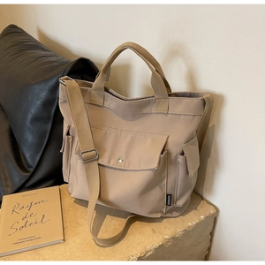 Khaki canvas tote bag detail featuring front flap pocket and adjustable fabric shoulder strap