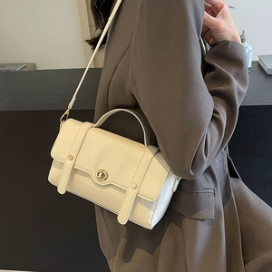 Sac à main chic en cuir crème avec fermoir pivotant doré et bandoulière sur mannequin