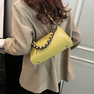Modern lime green cylinder crossbody bag with textured leather and bold chain strap
