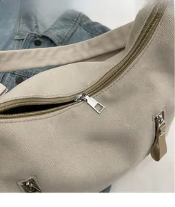 Détail macro des fermetures éclair en métal et tirettes en cuir sur un sac fourre-tout beige