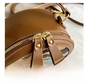 Close-up of smooth golden metal zippers and colorful woven texture on a round brown bag