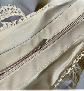 Detail of a smooth silver zipper closure on a straw woven bag with fabric lining