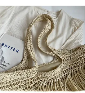Close-up of handmade straw tote bag with long tassels and woven handles for beach vacation