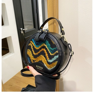 Detail view of woven pattern and gold embossed logo on a round leather crossbody bag
