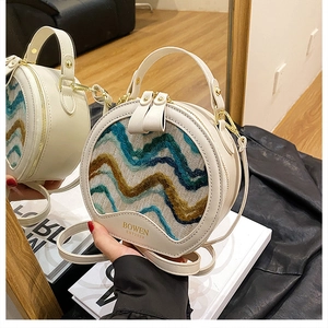 Detail of white round crossbody bag featuring blue wave weaving and gold hardware