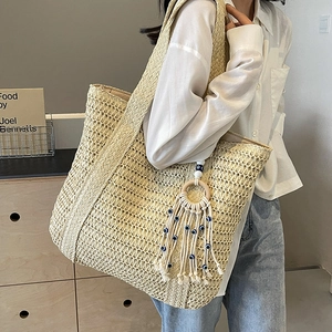 Large straw woven tote bag with evil eye tassel charm for beach and summer travel