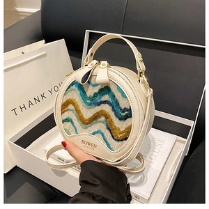 Detail of round crossbody bag featuring multi-color wavy weaving and gold-tone hardware