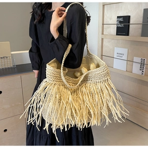 Close-up of bohemian beige straw tote bag with long tassel fringe and woven texture