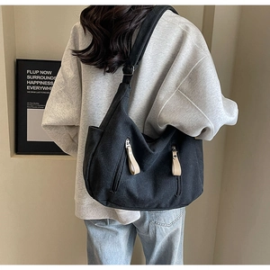 Détail du sac cabas en toile noire avec poches zippées verticales et tirettes en cuir
