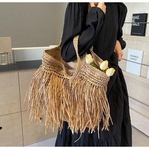 Close-up of a large straw tote bag with long tassels and bohemian fringe details
