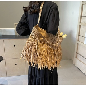 Detail of hand-woven straw tote bag with long tassels and comfortable shoulder strap