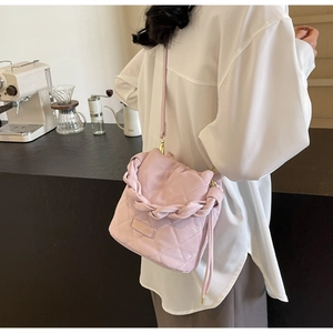 Rosa gesteppte Beuteltasche mit Flechtdetails, getragen in einem modernen Café-Ambiente