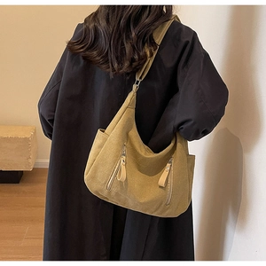 Détail du grand sac fourre-tout jaune moutarde porté par un mannequin en long manteau noir