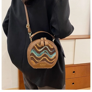 Detail of half-moon crossbody bag with wavy textured weave and leather strap on a model