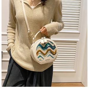 Detailed view of cream leather round handbag with colorful wave pattern and crossbody strap