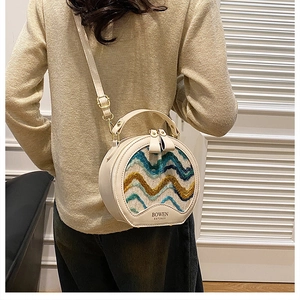 Detail of round crossbody bag with wave texture and adjustable leather shoulder strap