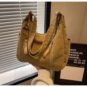 Détail du sac cabas en toile kaki montrant les poches zippées et tirettes en cuir