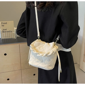 Detail einer gesteppten cremefarbenen Beuteltasche mit geflochtenem Griff und Gold-Dekor