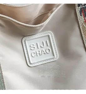 Macro detail of beige twill canvas bag featuring embossed logo and woven shoulder strap