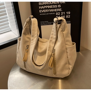 Détail du sac hobo en toile beige avec poches latérales et tirettes en cuir de luxe