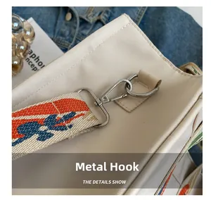 Detail shot of silver hardware hook and colorful jacquard woven strap on canvas tote bag