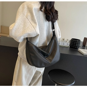 Detail of adjustable wide shoulder strap on a black nylon crossbody crescent bag