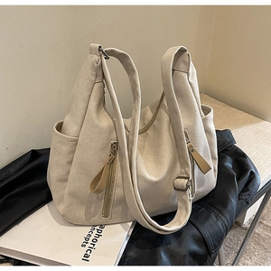 Détail du sac cabas en toile beige montrant la poche zippée et la bandoulière durable