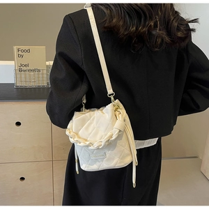 Detail der weißen gesteppten Beuteltasche mit Flechtgriff und Kordelzugverschluss
