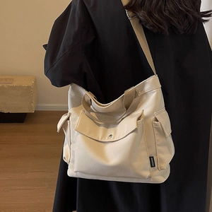 Minimalist beige canvas tote bag with large pockets and cross-body strap for women