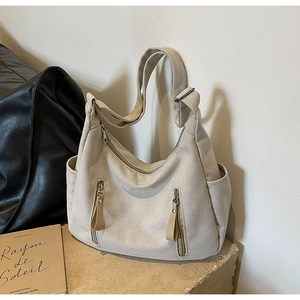 Détail du cabas en toile avec fermetures en cuir brun et large bandoulière beige