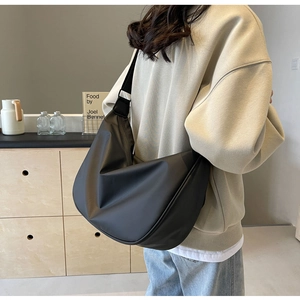 Detail view of large black oxford crossbody bag with wide strap and soft texture